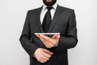 Sakallı bir erkek resmi iş kıyafetleri giyer yüksek teknoloji akıllı telefon cihazı taşır. İş elbisesi giymiş bir adam ve kravatlı küçük cep telefonlu bir adam tek elini kullanıyor.
