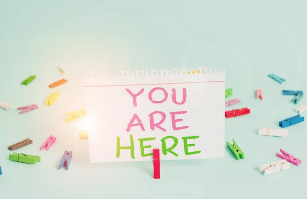 Word writing text You Are Here. Business concept for This is your location reference point global positioning system Colored clothespin rectangle square shaped paper light blue background.