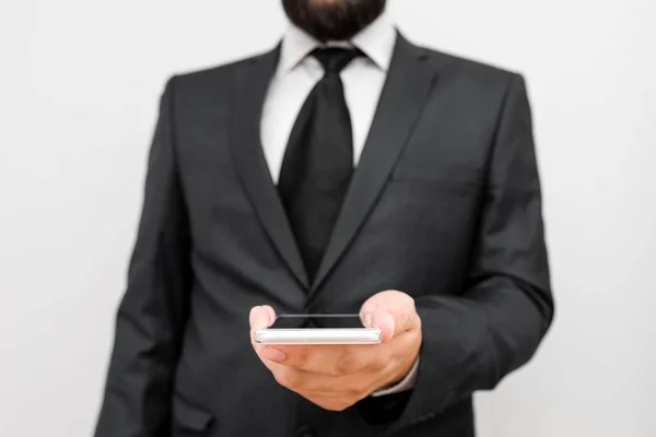 Άνδρας με γενειάδα φορούν επίσημα ρούχα εργασίας κατέχουν υψηλής τεχνολογίας συσκευή smartphone. Άνδρας ντυμένος με κοστούμι εργασίας συν γραβάτα κρατώντας μικρό κινητό hi τηλέφωνο τεχνολογίας χρησιμοποιώντας το ένα χέρι — Φωτογραφία Αρχείου