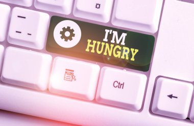 Writing note showing I M Hungry. Business photo showcasing having a strong wish or desire for something to put on stomach White pc keyboard with note paper above the white background.