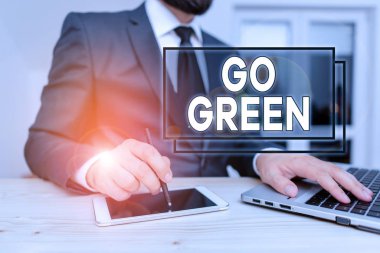 Go Green 'i gösteren bir not yazıyorum. İş fotoğraflarının gösteriminde, geri dönüşüm erkek kıyafetlerinin azaltılması konusunda çevre dostu kararlar alınırken Hitech akıllı telefonu kullanılıyor..