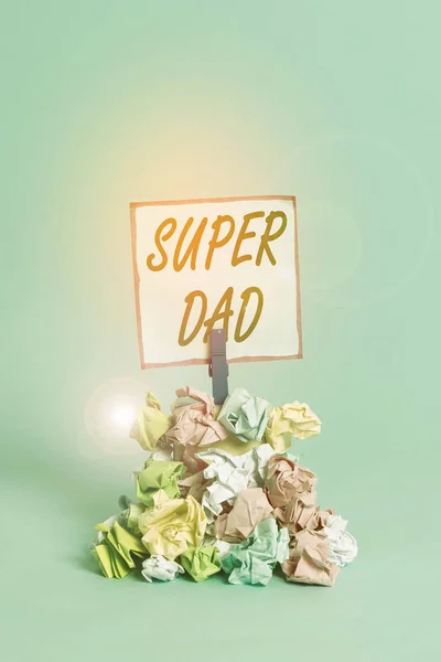 Handwriting text Super Dad. Concept meaning Children idol and super hero an inspiration to look upon to Reminder pile colored crumpled paper clothespin reminder blue background.