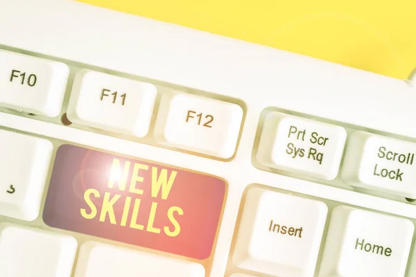 Text sign showing New Skills. Conceptual photo Recently Acquired Learned Abilities Knowledge Competences White pc keyboard with empty note paper above white background key copy space. — Stockfoto