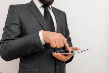 Erkek insan resmi iş kıyafetleri giyer yüksek teknoloji akıllı telefon cihazının sunumunu yapar. Takım elbiseli ve kravatlı bir adam küçük cep telefonu teknolojisi gösteriyor.
