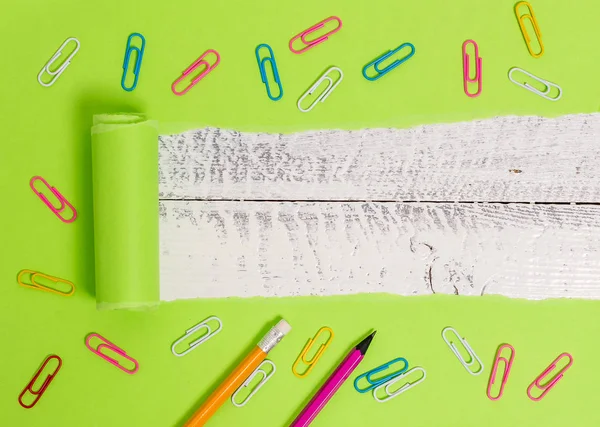 Cartão rasgado com clipe de papel colocado acima de uma mesa clássica de madeira. Papel rasgado espesso e estacionário em um pano de fundo de madeira texturizado. Maneira artística de organizar plana coloca a fotografia — Fotografia de Stock