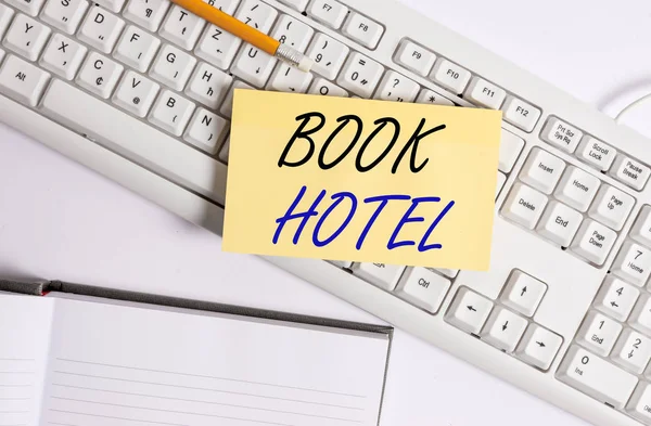 Texto de escritura de palabras Book Hotel. Concepto de negocio para un arreglo que se hace para tener una habitación de hotel o alojamiento Teclado de PC blanco con papel de nota vacío y clips de papel sobre fondo blanco . — Foto de Stock