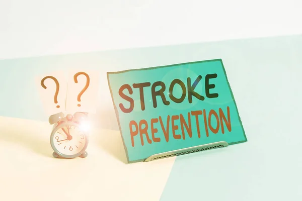 Writing note showing Stroke Prevention. Business photo showcasing identified demonstratingal risk factors and change lifestyle Alarm clock beside a Paper sheet placed on pastel backdrop.