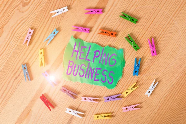 Word writing text Helping Business. Business concept for improving some measure of an enterprise s is success Colored clothespin papers empty reminder wooden floor background office.