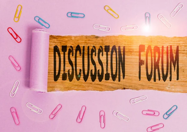 Conceptual hand writing showing Discussion Forum. Business photo showcasing section of a website that is used for public discussion Paper clip and torn cardboard on wood classic table backdrop.