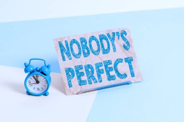 Mesaj işareti kimsenin mükemmel olmadığını gösteriyor. Kavramsal fotoğraf herkesin hata ya da hata yaptığını söyler. Mini boyunda çalar saat, pastel arka plana yaslanmış kağıt bir çarşaf yanında..