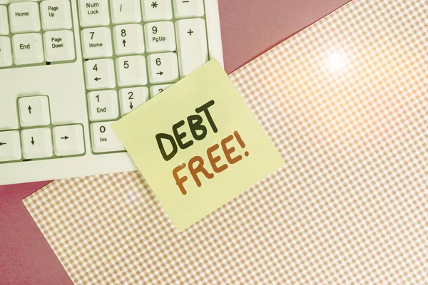 Text sign showing Debt Free. Conceptual photo does not owning any money to any individual or companies Note paper stick to computer keyboard near colored gift wrap sheet on table.