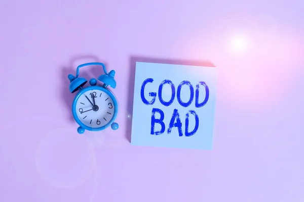 Writing note showing Good Bad. Business photo showcasing to seem to be going to have a good or bad result Life choices Vintage alarm clock wakeup blank notepad sticky note colored background.