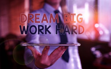 Dream Big Work Hard'ı gösteren bir not yazıyorum. İş fotoğraf vitrin kendinize inanın ve boş alanda parmak ile işaret arka planda bulanık kadın hayalleri ve hedefleri izleyin.