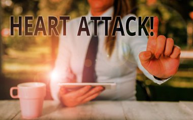 Kalp Krizini gösteren kavramsal el yazısı. Ölümle sonuçlanan koroner trombozun ani ortaya çıkması İş fotoğrafı metin Kadın iş adamı masaya oturan ve cep telefonu tutan.