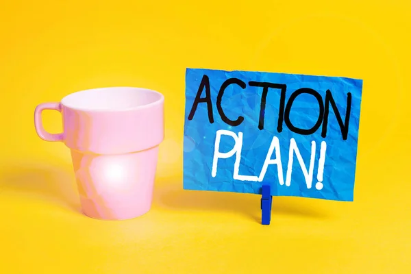 Handwriting text Action Plan. Concept meaning proposed strategy or course of actions for certain time Cup empty paper blue clothespin rectangle shaped reminder yellow office.