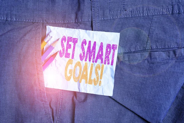 Text sign showing Set Smart Goals. Conceptual photo list to clarify your ideas focus efforts use time wisely Writing equipment and white note paper inside pocket of man work trousers.