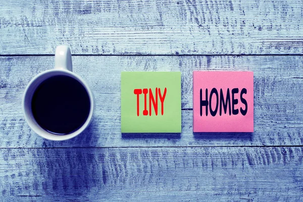 Handwriting text writing Tiny Homes. Concept meaning houses contain one room only or two and small entrance Cheap Stationary placed next to a cup of black coffee above the wooden table.