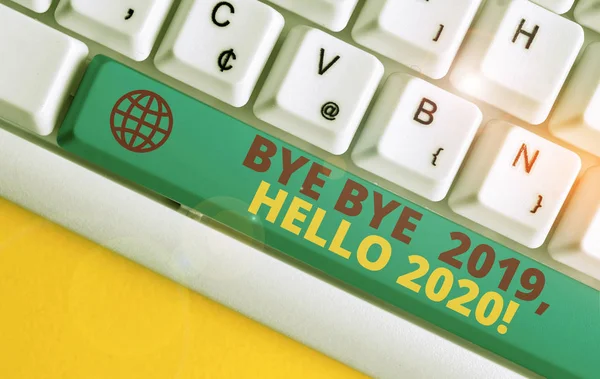 Escribir a mano conceptual mostrando Bye Bye 2019 Hola 2020. Foto de negocios mostrando diciendo adiós al año pasado y dando la bienvenida a otro buen teclado de PC blanco con papel de nota sobre el fondo blanco —  Fotos de Stock