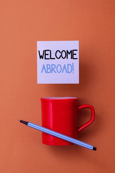 Escrevendo uma nota mostrando Welcome Abroad. Foto de negócios mostrando algo que você diz quando alguém entra no navio Vista frontal xícara de café colorido nota pegajosa caneta gema de fundo de cor . — Fotografia de Stock