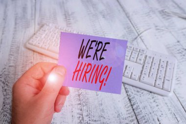 İşe Aldığımızı gösteren bir metin işareti. Kavramsal fotoğraf son zamanlarda birini istihdam veya renkli hatırlatma kare şeklinde kağıt beyaz klavye ahşap zemin tutan belirli bir iş adam yapmak için birisi ödemek.