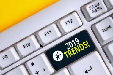 Kelime yazma metni 2019 Trendler. Beyaz arka plan tuşu kopyalama alanının üzerinde boş not kağıdı yla beyaz bilgisayar klavyesi geliştiren veya değiştiren genel yön için iş kavramı.