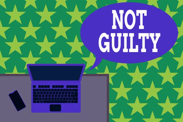 Handwriting text Not Guilty. Concept meaning someone is innocent didnt commit specific crime He free Upper view office working place laptop lying wooden desk smartphone side.