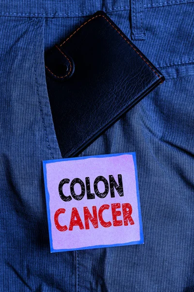 Handwriting text writing Colon Cancer. Concept meaning the development of cancer cells from the colon or rectum Small little wallet inside man trousers front pocket near notation paper.