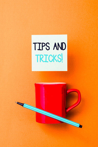 Writing note showing Tips And Tricks. Business photo showcasing means piece advice maybe suggestion how improve Front view coffee cup colored sticky note pen yolk color background.