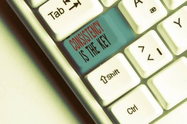 Tutarlılığı gösteren bir not yazmak anahtardır. Bir göreve tam adanmışlık gösteren iş fotoğrafı beyaz arkaplan üzerinde not kağıdı olan bir alışkanlık oluşturma işlemi beyaz pc klavye.