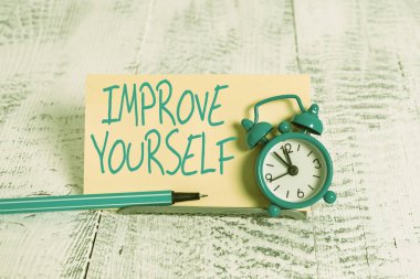 Handwriting text Improve Yourself. Concept meaning making yourself a better or more knowledgable demonstrating Mini blue alarm clock stand tilted above buffer wire in front of notepaper.