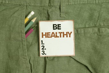 Sağlıklı Olun 'u gösteren bir not yazıyorum. İş fotoğraflarının sergilenmesi güçlü ve bedensel ya da zihinsel hastalıklardan tamamen arınmış. Pantolon cebinde ekipman ve mavi not kağıdı var..