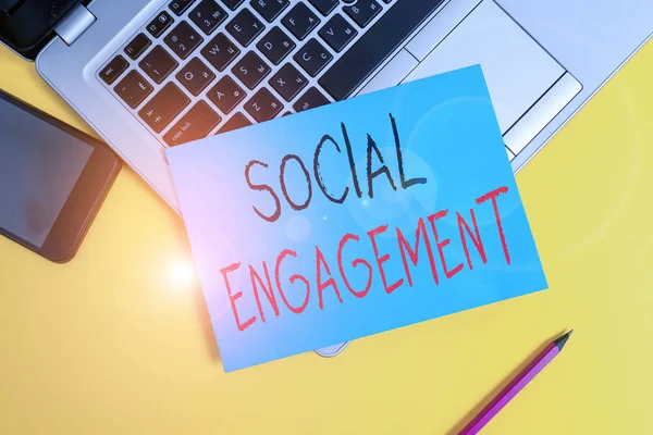 Writing note showing Social Engagement. Business photo showcasing one s is degree of participation in a community or society Metallic laptop small paper sheet pencil smartphone colored background. — Stockfoto