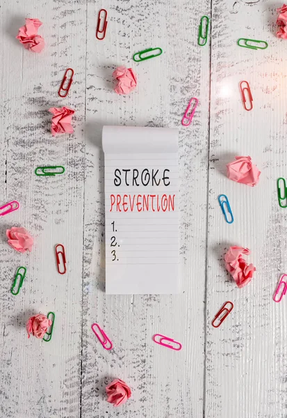 Writing note showing Stroke Prevention. Business photo showcasing identified demonstratingal risk factors and change lifestyle Stripped ruled notepad clips paper balls wooden background.