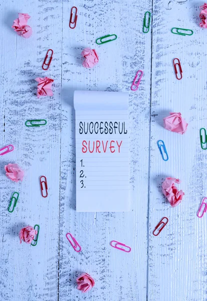 Writing note showing Successful Survey. Business photo showcasing measure of opinions or experiences of a group of showing Stripped ruled notepad clips paper balls wooden background.