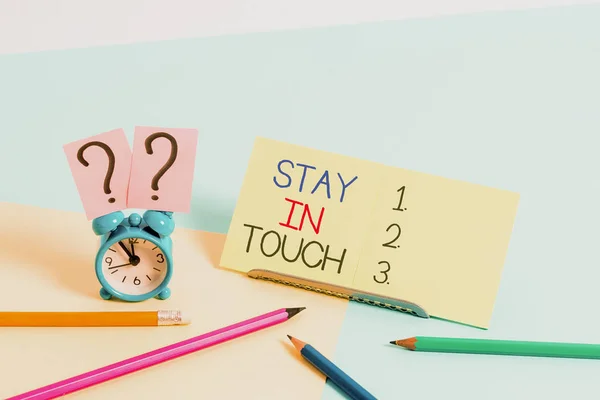 Text sign showing Stay In Touch. Conceptual photo Keep Connected thru Phone Letters Visit Email Social Media Mini size alarm clock beside stationary placed tilted on pastel backdrop. — ストック写真