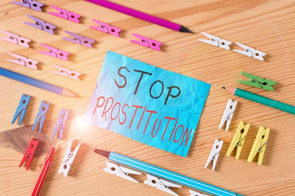 Conceptual hand writing showing Stop Prostitution. Business photo showcasing end the engaging sexual activity in exchange for payment Colored crumpled papers wooden floor background clothespin.