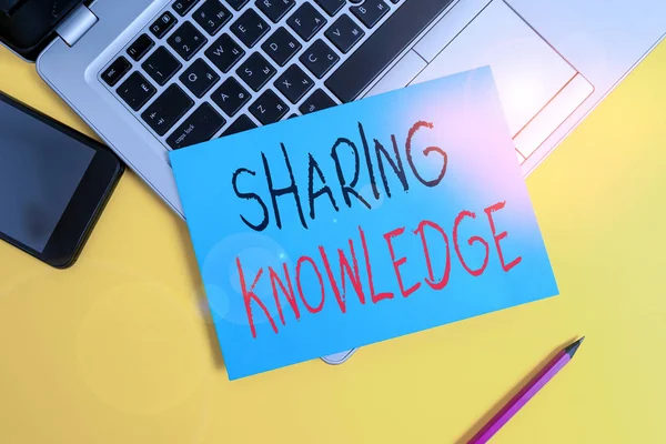 Writing note showing Sharing Knowledge. Business photo showcasing knowledge is exchanged among showing or organizations Metallic laptop small paper sheet pencil smartphone colored background.