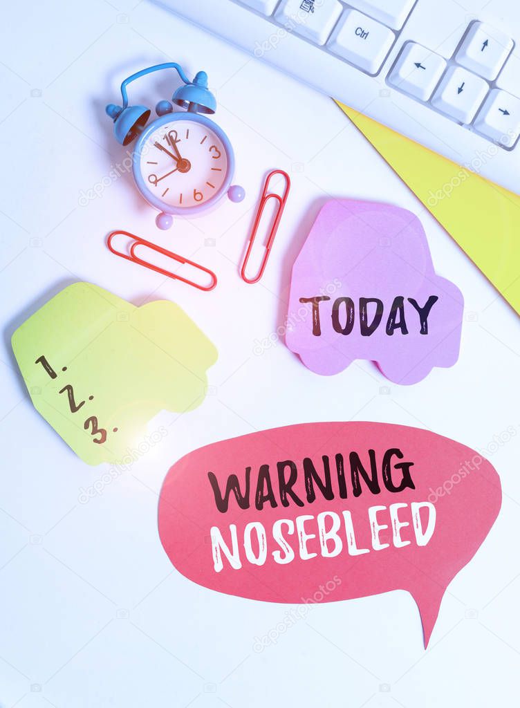 Writing note showing Warning Nosebleed. Business photo showcasing caution on bleeding from the blood vessels in the nose Flat lay with copy space on bubble paper clock and paper clips.