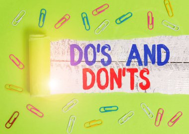 Mesaj işareti Do S ve Don T 'leri gösteriyor. Kavramsal fotoğraf. Teknolojik bir komplikasyon. Kağıt ataç ve karton yırtılması, klasik tahta masa arkaplanının üzerine yerleştirilmiş..