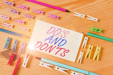 Handwriting text Do S And Don Ts. Concept meaning Technologically complication of making a decision Colored clothespin papers empty reminder wooden floor background office.