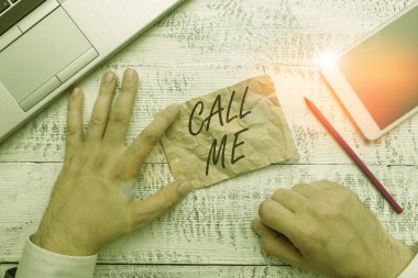 Writing note showing Call Me. Business photo showcasing Asking for communication by telephone to talk about something Hand hold note paper near writing equipment and smartphone.