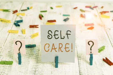 Writing note showing Self Care. Business photo showcasing practice of taking action preserve or improve ones own health Crumbling sheet with paper clips placed on the wooden table.