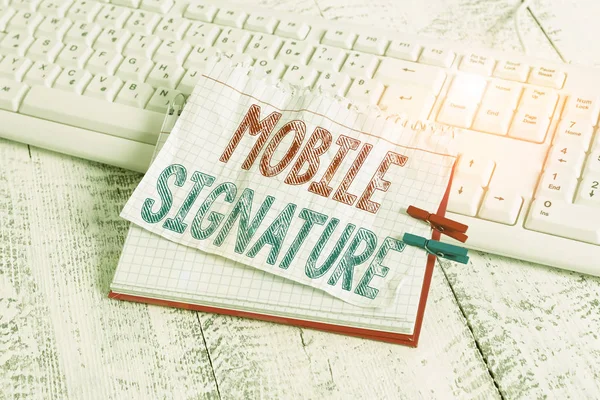 モバイル署名を示すテキスト記号。携帯電話のノートブックのいずれかに生成された概念的な写真のデジタル署名メモ帳の服ピン固定シートホワイトキーボードライト木製. — ストック写真