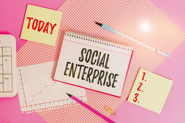 Text sign showing Social Enterprise. Conceptual photo commercial organization that has specific social objective Writing equipments and computer stuffs placed above colored plain table.
