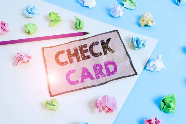 Handwriting text writing Check Card. Concept meaning allows an account holder to access funds in her account Colored crumpled papers empty reminder blue yellow background clothespin.