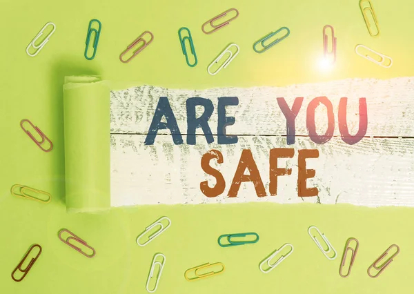 Text sign showing Are You Safe. Conceptual photo Free from danger Not anticipating any Harm Hurt physically Paper clip and torn cardboard placed above a wooden classic table backdrop.