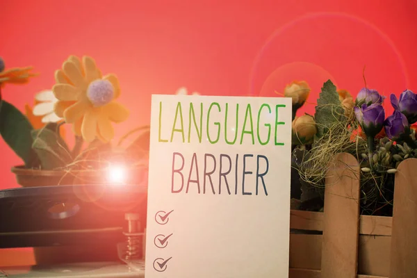Writing note showing Language Barrier. Business photo showcasing difficulties in communication Speaking different language Flowers and writing equipments plus plain sheet above textured backdrop.