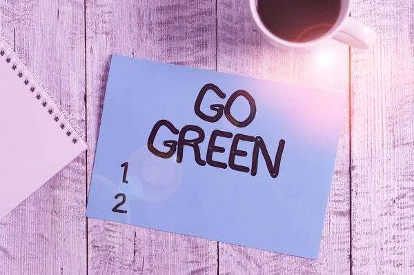 Manuscrito texto escrevendo Go Green. Conceito que significa tomar decisões mais ecológicas como reduzir a reciclagem Estacionário colocado ao lado de uma xícara de café preto acima da mesa de madeira . — Fotografia de Stock