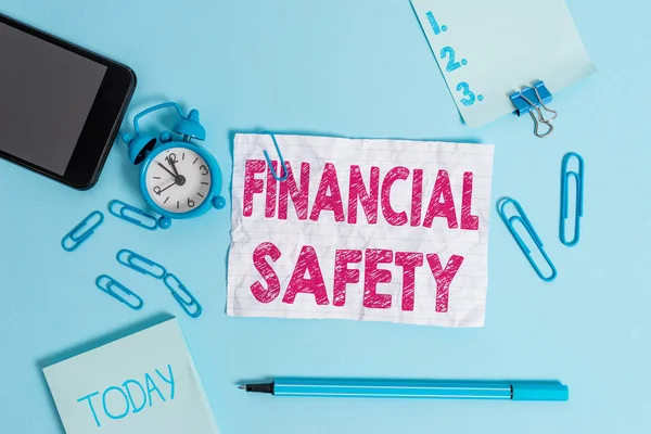 Text sign showing Financial Safety. Conceptual photo enough money saved to cover emergencies and financial goals Alarm clock clips notepad smartphone rubber band marker colored background.