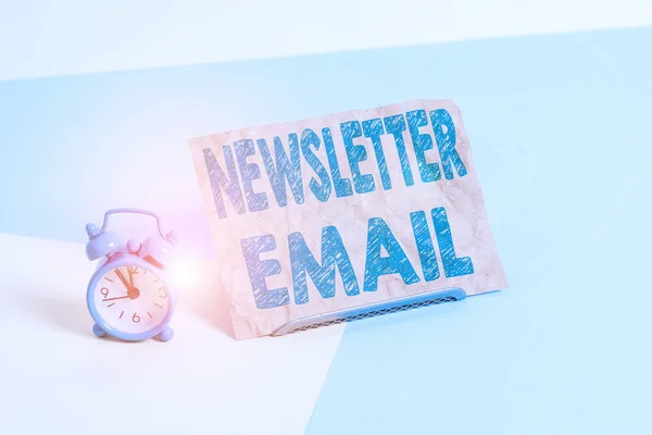 Text sign showing Newsletter Email. Conceptual photo email sent to subscribers informing them about the news Mini size alarm clock beside a Paper sheet placed tilted on pastel backdrop.